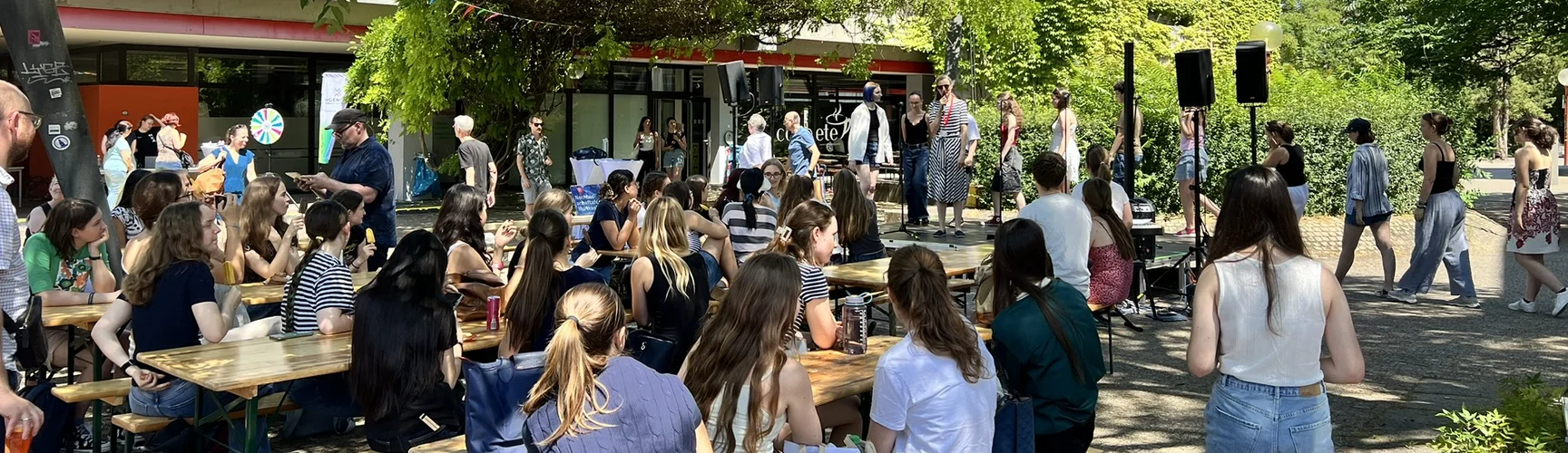 Studierende sitzen auf Bierbänken auf dem geschmückten Campus