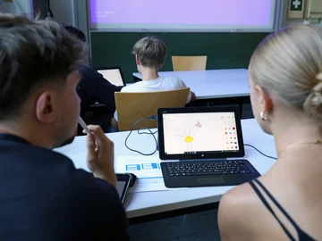 Zwei Schüler:innen sitzen an einem Laptop und konstruieren eine Blume.