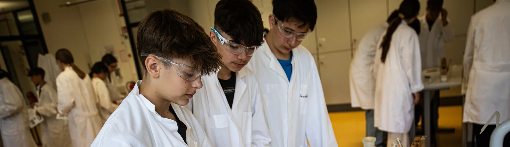 Drei Schüler mit Schutzbrillen bei einem chemischen Experiment