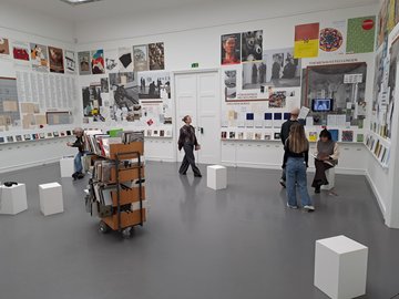 Mehrere Menschen sind in einem Raum in der Kunsthalle Baden-Baden, an den Wänden verschiedene Plakate.
