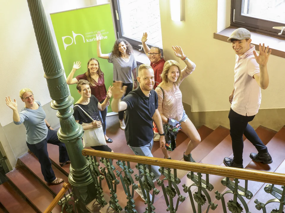 Studierende laufen auf einer Treppe hoch und runter und winken in die Kamera