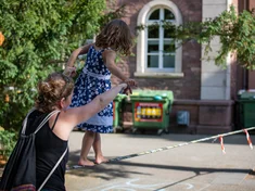 eine junge Frau spielt mit ihrer Tochter auf dem Campus