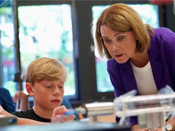 Die Ministerin schaut einem Schüler beim Experimentieren über die Schulter.
