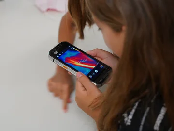 Eine Schülerin sieht auf einen Handy-Bildschirm mit einem Wärmebild.