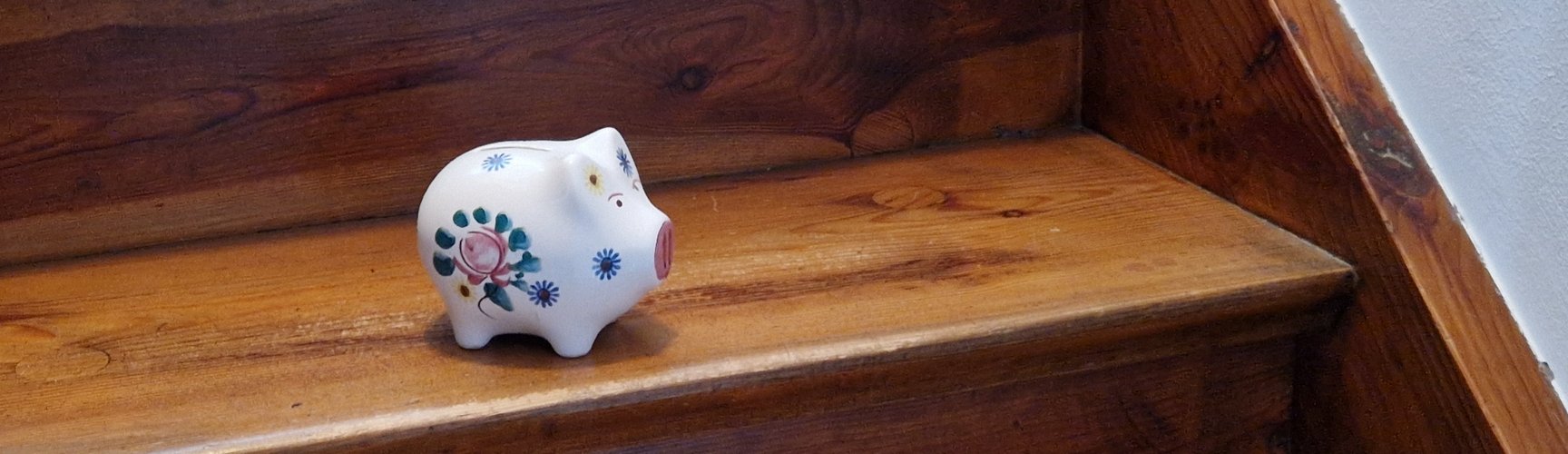 Ein Sparschwein steht auf einer Holztreppe