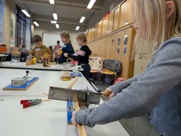 Ein Mädchen arbeitet mit einer Säge an einem Werktisch