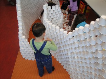 Ein Kind baut hohe Mauern aus Eisbechern.