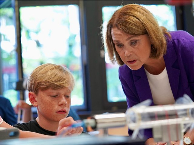 Die Ministerin schaut einem Schüler beim Experimentieren über die Schulter.