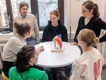 ein Gruppe aus Dozentinnen und Studierenden diskutieren Lehrinhalte 