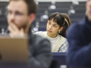 Eine Studentin folgt in einem Hörsaal einem Vortrag.