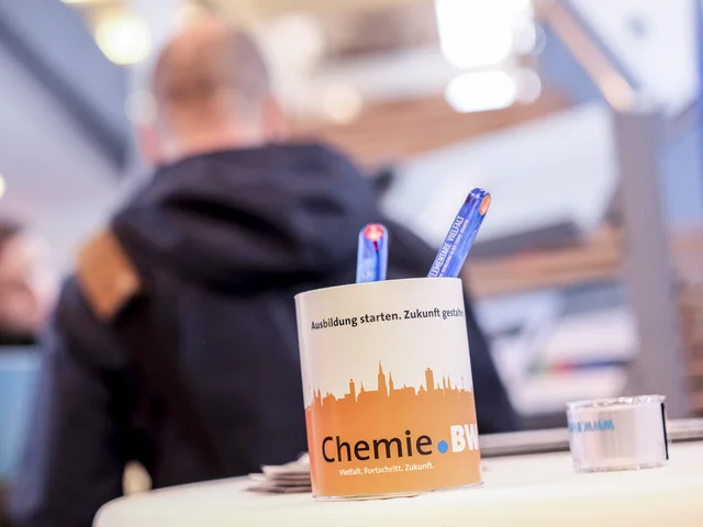Nahaufnahme einer Tasse mit Chemie-BW-Logo. Menschen im Hintergrund.