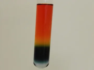 Ein Reagenzglas enthält eine in Schichten mehrfarbige Flüssigkeit.