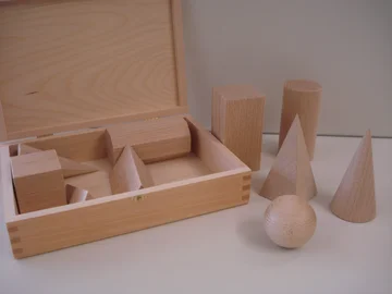 Verschiedene Körper aus Holz auf einem Tisch: Würfel, Kugel, Quader, Kegel usw,
