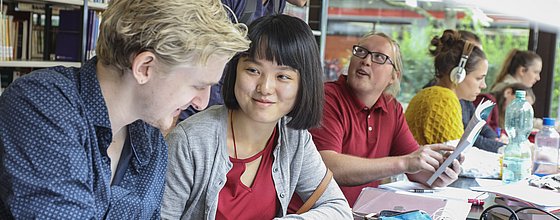 Studierende lernen im ruhigen Bereich der Bibliothek der PH Karlsruhe. Hinter ihnen, sind Bücherregale zu sehen. Sie befinden sich im Gebäude 2. 