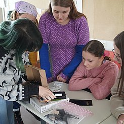 zu sehen sind Schülerinnen, die das Co2-Messgerät betrachten.