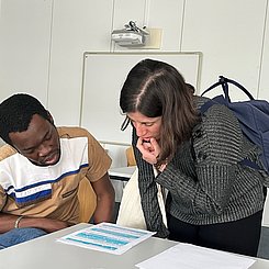 Zwei Studierende schauen sich ein Handout an.